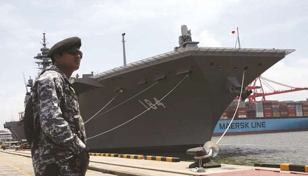 A Sri Lankan marine stands guard in front of Japanese helicopter carrier Kaga docked at Colombo port in Sri Lanka yesterday.