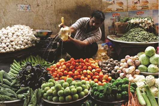 A vegetable seller sprinkles water to keep them fresh and shine at a makeshift stall along a market in Karachi. Pakistan rupee devaluation of 7.8% with gas tariff hike will increase commodity prices by 15% to 25%, pushing inflation to double digits in the months ahead, analysts said.