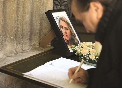 A man writes in the condolence book near a picture of Marinova.