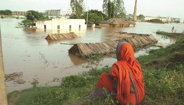 A woman watches helplessly as a flood submerges her thatched-roof home containing all her possessions on the outskirts of Bhubaneswar city in Indiau2019s eastern state of Odisha.