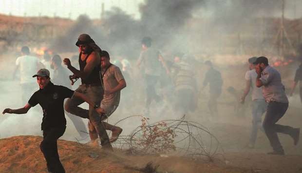 Palestinian demonstrators run during a protest calling for lifting the Israeli blockade on Gaza and demanding the right to return to their homeland, at the border fence in the southern Gaza Strip, yesterday.