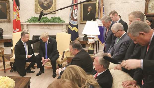 Trump and Brunson participate in a prayer at the Oval Office. Also seen are members of Congress and administration officials.