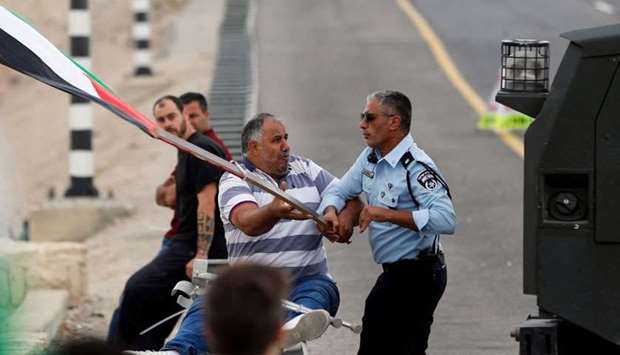 An Israeli policeman attempts to take a flag away from a Palestinian