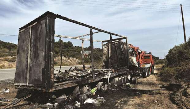 The burned truck is pictured in Sarakina, near Kavala, northern Greece yesterday. Eleven people died after a car thought to be carrying migrants crashed head-on with a truck and burst into flames, police said.