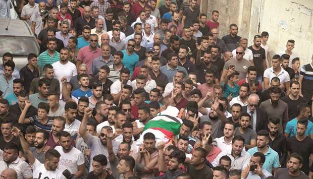 Palestinians carry the body of 48-year-old mother of eight, Aisha Rabi, who died of her wounds after the car she was travelling in with her husband was hit by stones, during her funeral in the West Bank village of Bidya, near Salfit, yesterday.