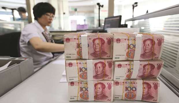 Yuan banknotes are placed on a staffu2019s table in a bank in Lianyungang, Chinau2019s Jiangsu province. The yuan edged close to 7 last week after the Peopleu2019s Bank of China announced a cut to the reserve requirement ratio for a fourth time this year,  reflecting growing divergence with US monetary policy.