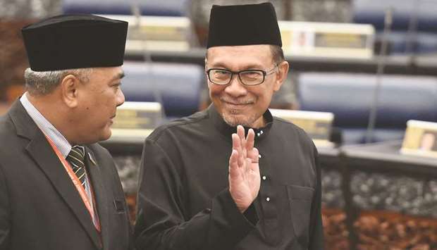Malaysiau2019s Peopleu2019s Justice Party president and leader of the Pakatan Harapan coalition Anwar Ibrahim (right) waves before taking an oath as a member of the parliament during a swearing-in ceremony at the Parliament House in Kuala Lumpur.