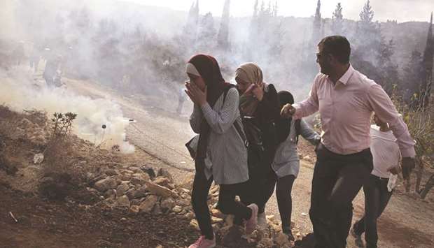 Palestinians run away from tear gas fired by Israeli forces during clashes over an order to shut down a Palestinian school in the town of As-Sawiyah, south of Nablus in the occupied West Bank, yesterday.
