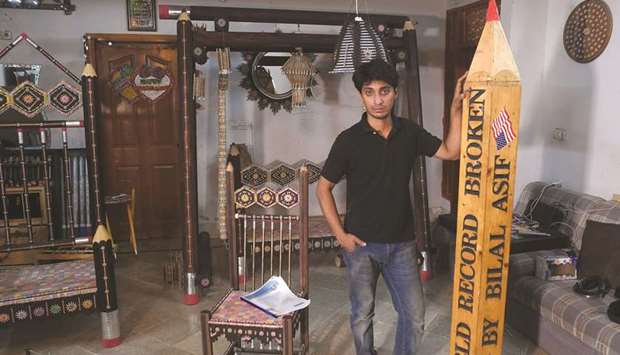 In this photograph taken on October 4, artist Bilal Asif poses for a photograph with his pencils artwork at his studio in Karachi.