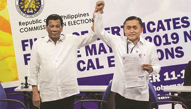 President Rodrigo Duterte raises the hand of his top aide Christopher Lawrence u201cBongu201d Go, after he filed his certificate of candidacy.