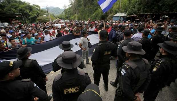 Guatemala's police officers stand as Honduran migrants, part of a caravan trying to reach the US, arrive to the border between Honduras and Guatemala, in Agua Caliente, Guatemala.
