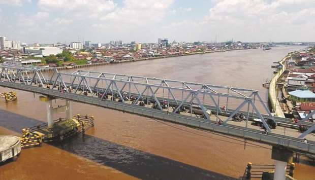 Traffic moves along a bridge across the Kapuas river in this aerial photograph taken in Pontianak, West Kalimantan, Indonesia, on May 5, 2018. With the World Bank estimating Indonesiau2019s infrastructure investment requirement at $500bn by 2022, the government is turning to private and foreign investors for funds. The renewed efforts to tap idle Islamic endowment funds will also ease pressure on state companies to raise funds at high interest rates from a market rattled by a slumping currency and soaring bond yields.