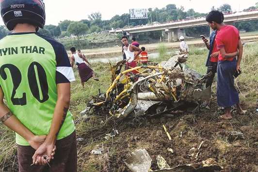 People look at the wreckage of a crashed military plane at a field in Magway yesterday.