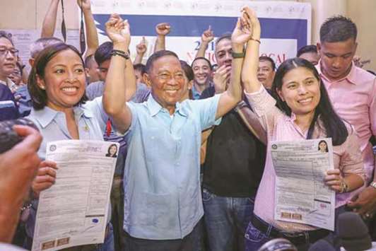 Former vice president Jejomar Binay raises the hand of daughter Abby (left), mayor of Makati City, and her running-mate, Vice Mayor Monique Lagdameo, after the two filed their certificates of candidacy.