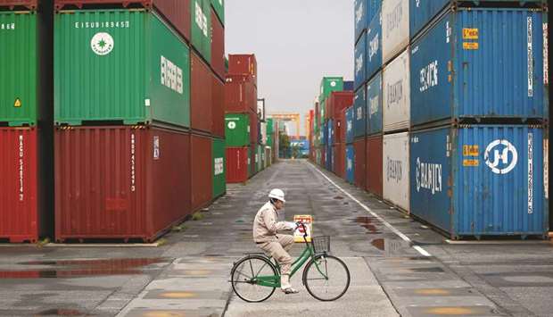 A worker rides a bicycle in a container area at a port in Tokyo. Japanese exports fell 1.2% in September from a year earlier, ministry of finance data out yesterday showed.