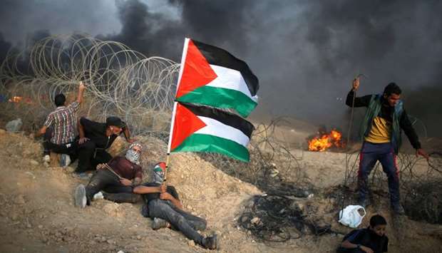 Palestinian demonstrators take cover next to Israeli wire during a protest calling for lifting the Israeli blockade on Gaza and demanding the right to return to their homeland, at the Israel-Gaza border fence in Gaza
