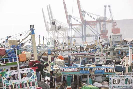 Fishing boats sit moored at the harbour as gantry cranes stand in the background at Gwadar Port in Pakistan. Foreign investors have held back new investment plans as they wait for clarity on the economic front in Pakistan.