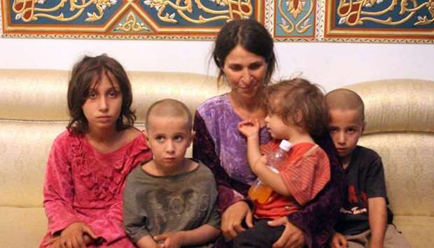 A woman and four children among the six released of 27 Druze hostages held by the Islamic State (IS) group in a prisoner swap and ransom, upon their arrival at a government-controlled building in Syria's southern city of Sweida. A handout picture released by the official Syrian Arab News Agency (SANA). 