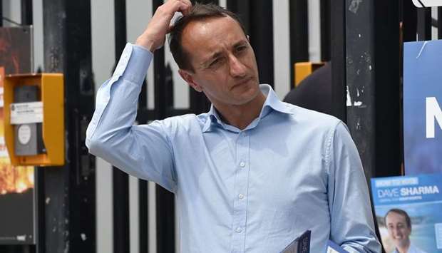Liberal Party candidate for Wentworth Dave Sharma (L) waits for voters outside a polling station during the Wentworth by-election in Bondi Beach in Sydney.