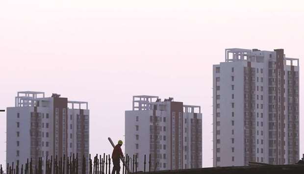 A worker stands on the scaffolding at a construction site against a backdrop of residential buildings in Huaian, Jiangsu province. Average new home prices in Chinau2019s 70 major cities rose 0.9% in September from a month earlier, Reuters calculated from official data published yesterday.