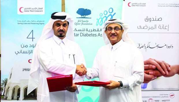 Executive Director of Qatar Diabetes Association Dr Abdullah Omar al-Hamaq and Executive Director of QRCS Yousef Abdullah al-Sada exchange documents after signing the MoU