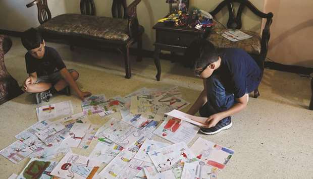 Gabriel Moncada (right) looks at his drawings on the floor at his home in Caracas.