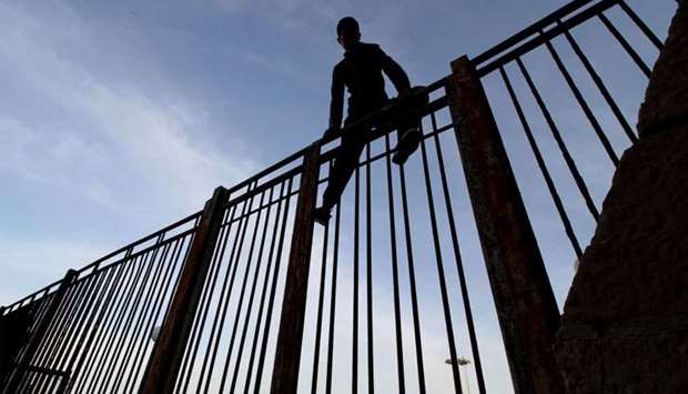 Moroccan youngster climbs a fence in the port of the Spanish enclave of Melilla bordering Morocco
