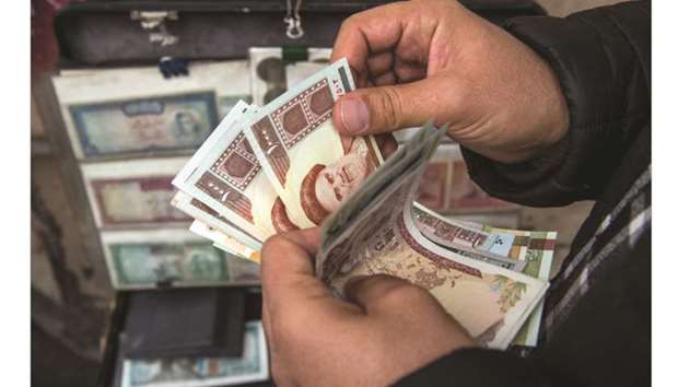A currency trader counts Iranian rial banknotes at a money exchange market on Ferdowsi street in Tehran (file). The rial has plunged 70% against the US dollar in the free market this year, but Iranu2019s financial system has been able to ride out past periods of sanctions, and officials say they are working on new products to stimulate capital markets activity.