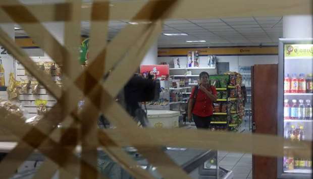 A woman is pictured inside a store with taped-up glass panels to protect against the expected severe winds of Hurricane Willa as it approaches the Pacific beach resort of Mazatlan, Mexico
