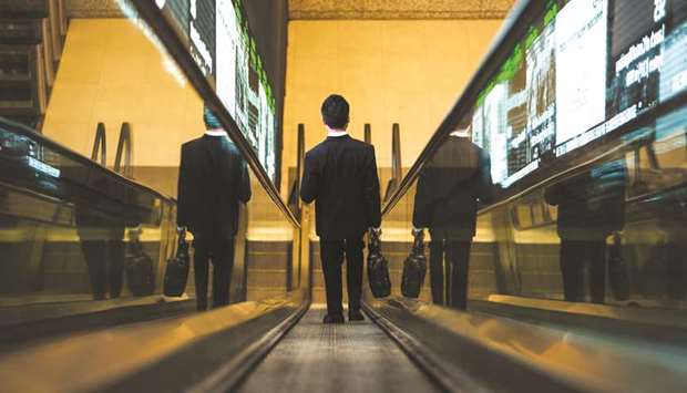 A man rides an escalator past an electronic screen at the Singapore Exchange (SGX) headquarters in Singapore (file). Launched by FTSE Russell, the FTSE ST Singapore Shariah Index tracks companies listed on the Singapore Exchange and selects them in accordance to their Shariah-compliance as demand for Islamic investment products continues to see stable growth in the region.