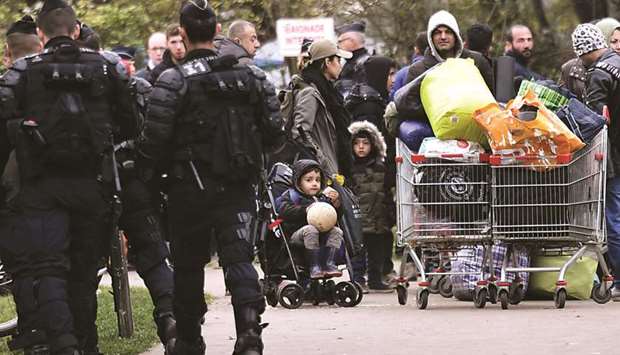 Migrants are seen with their belongings during a police operation to clear a migrant camp in Grande Synthe, northwestern France.