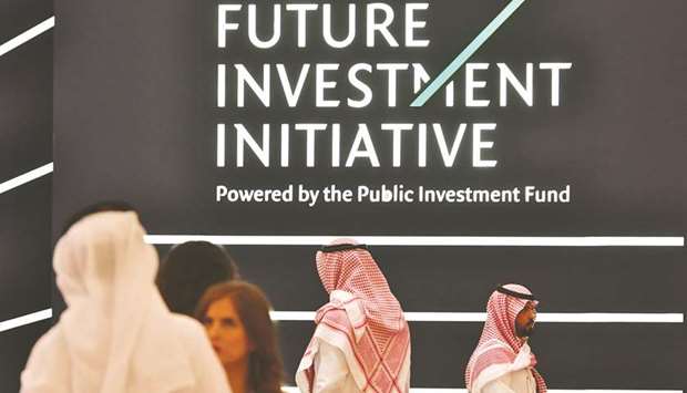 People walk past a sign of the Future Investment Initiative in the Saudi capital Riyadh yesterday. The three-day conference that seeks to project the oil-rich kingdom as a lucrative business destination appeared to largely be a subdued affair after the Khashoggi murder pushed the worldu2019s top oil exporter into one of its worst crises.