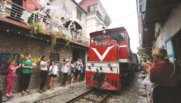 A group of tourists taking photo of a train passing through an old residential district in central Hanoi.