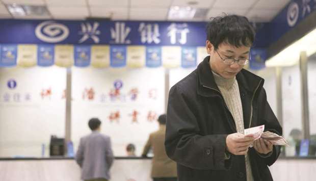 A customer counts his yuan notes at a branch of Industrial Bank in Shanghai (file). The yuan has tumbled 9% against the dollar in the past six months, dragged down by trade tension with the US and bets of further monetary easing by the Peopleu2019s Bank of China.