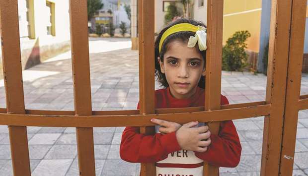 This picture taken on September 14, shows Syrian girl Jasmine Dabash posing behind the gate of a school next to Albaniau2019s National Reception Centre for Asylum Seekers, Tirana.