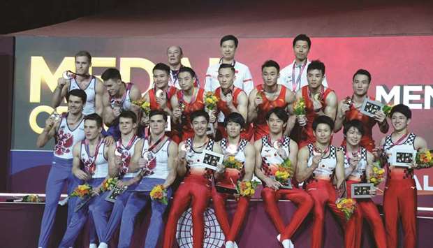 Winners China (in red) pose on the podium with second-placed Russia (in white and blue) and third-placed Japan (in white and red) after the menu2019s team final at the 48th Artistic Gymnastics World Championships Doha 2018 at Aspire Dome yesterday. PICTURES: Thajudheen