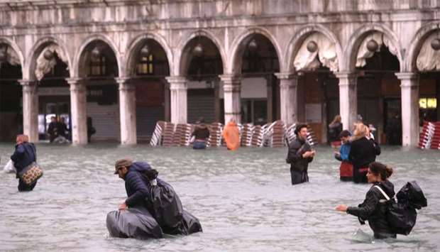 People walk in a flooded Saint Mark Square in Venice