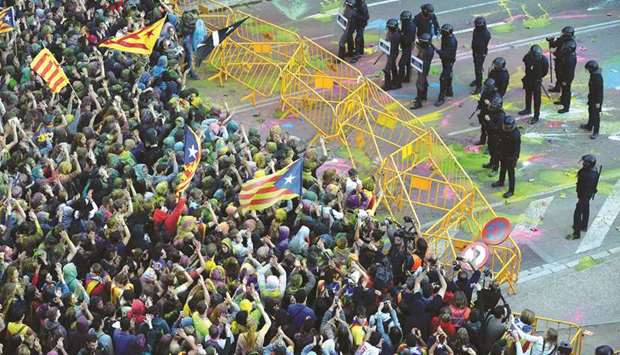 This picture taken late on Monday shows Catalan u2018Mossos Du2019Esquadrau2019 regional police officers behind a security barrier as protesters gather in front of the Spanish governmentu2019s local office in Girona.