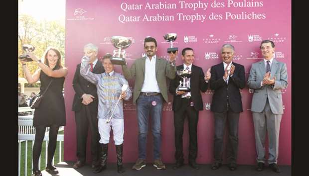 HE Sheikh Joaan bin Hamad al-Thani (centre) lifts the trophies as His Highness Sheikh Abdullah bin Khalifa al-Thani (second from right) applauds after Al Shaqab Racingu2019s Al Haffanah, trained by Thomas Fourcy (third from right) and ridden by Julien Auge (third from left), won the Qatar Arabian Trophy des Pouliches (Group 1 PA) at Saint Cloud, near Paris, France, yesterday.