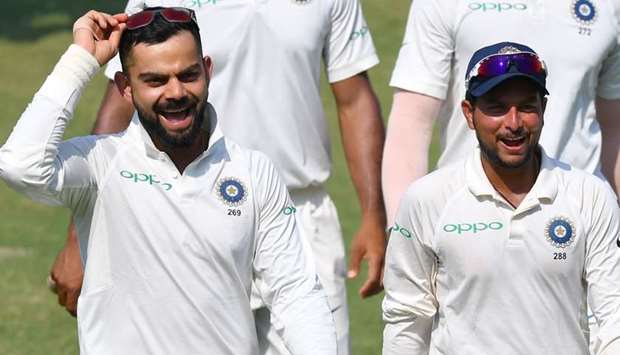 Indian captain Virat Kohli alongwith teammate Kuldeep Yadav laugh as they walk back after winning the first Test cricket match between India and West Indies at the Saurashtra Cricket Association Stadium in Rajkot. AFP
