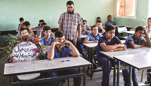Palestinian schoolboys sit in a class with a flower bouquet in the seat of their late classmate, the 14-year-old Fares Hafez al-Sersawi who was killed the day before during clashes with  Israeli forces by the border fence, in a school in Gaza City, yesterday.