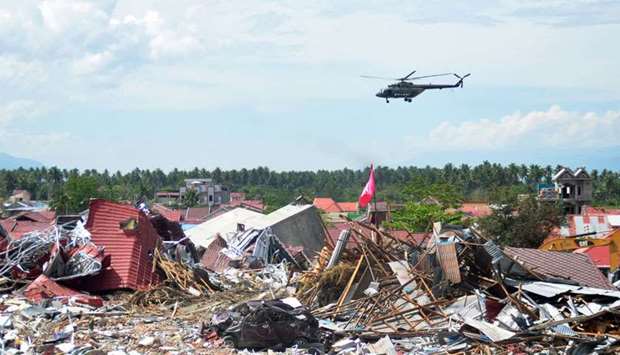 A military helicopter flies past a devastated area in Palu