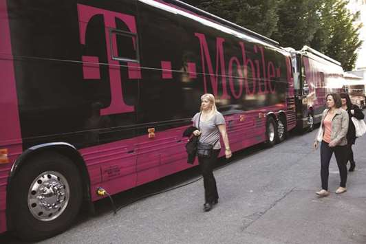 Women walk past buses displaying T-Mobile US logos outside the Paramount Theatre during an event in Seattle. T-Mobile says in a filing that cable providers getting into the wireless business shows u201cthe intensity of current competition in the sector.u201d