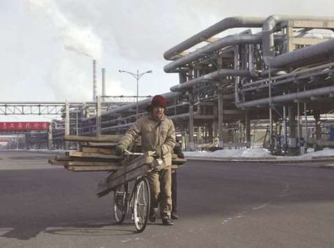 A man pushes his bike through a petrochemical plant in Daqing, China (file). Despite government efforts to cut pollution and carbon emissions from oil and gas, the IEA said it expected the rapid growth of emerging economies, such as India and China, to propel demand for petrochemical products.