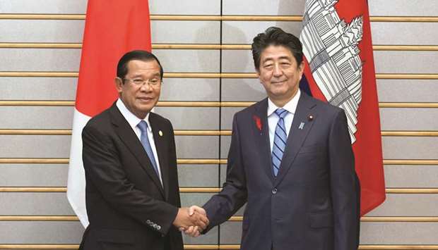 Japanese Prime Minister Shinzo Abe, right, and Cambodiau2019s Prime Minister Hun Sen shake hands prior to their meeting at Abeu2019s office in Tokyo yesterday.