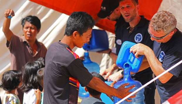 Members of Germany's NGO organisation ISAR-Germany (International Search and Rescue) give purified water to people at a suburb of Palu, Central Sulawesi, Indonesia