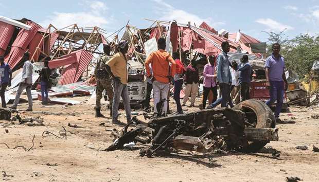 Bystanders gather at the site of a suicide car bomb explosion which targeted a European Union vehicle convoy in Mogadishu, Somalia, yesterday.