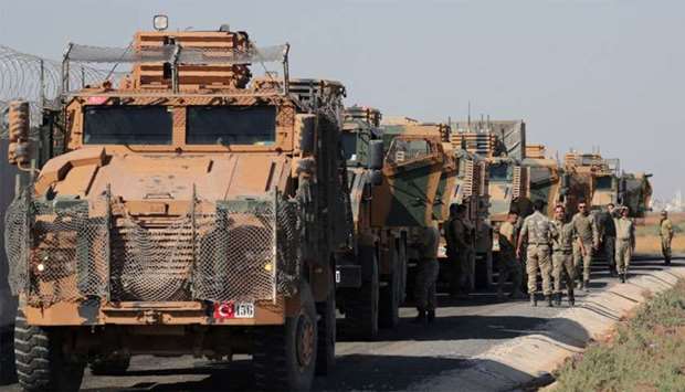 Turkish soldiers stand near military trucks in the village of Yabisa, near the Turkish-Syrian border