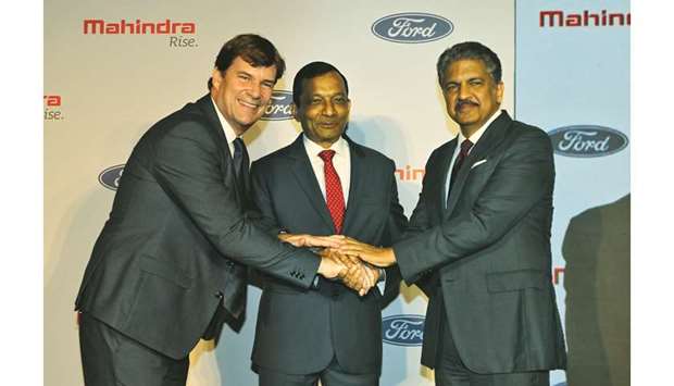 Jim Farley, president of Ford New Businesses, Technology and Strategy; Pawan Goenka, managing director of Mahindra and Mahindra Limited and Anand Mahindra, chairman of Mahindra Group, join their hands after attending a news conference in Mumbai yesterday. Under pressure from shareholders to make profits, Ford has been globally restructuring its businesses with an aim to save $11bn over the next few years.