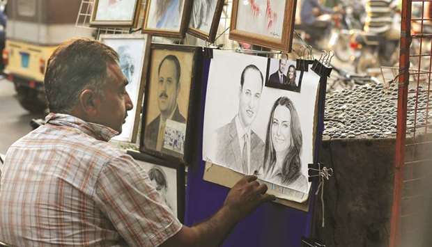 Street artist Mohamed Zaffar, 54, draws a sketch of Britainu2019s Prince William and Catherine, Duchess of Cambridge, ahead of their visit, from a makeshift stall along a sidewalk in Karachi.